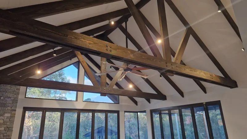 Track lighting beneath exposed timber trusses in a private residence.